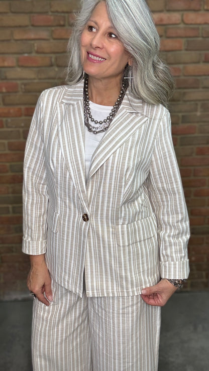 Woman wearing a Linen Stripped Blazer and Linen Stripe Pant standing against a brick wall.