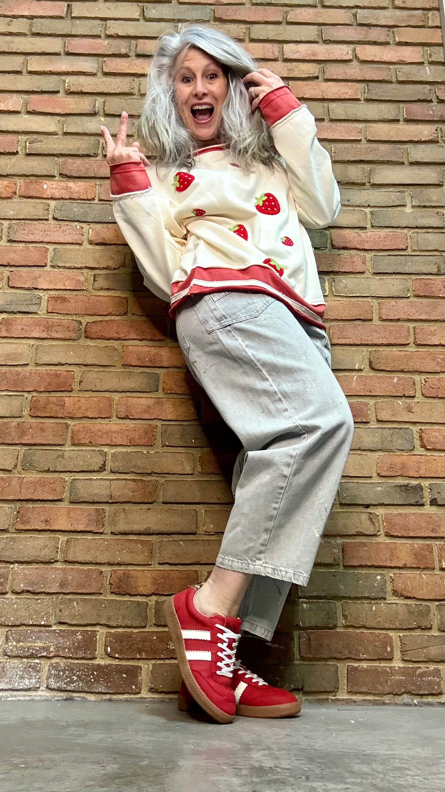 Person wearing Oyster Grey Big Pocket Jeans paired with Strawberry Sweatshirt and Heads Up Red Shoes