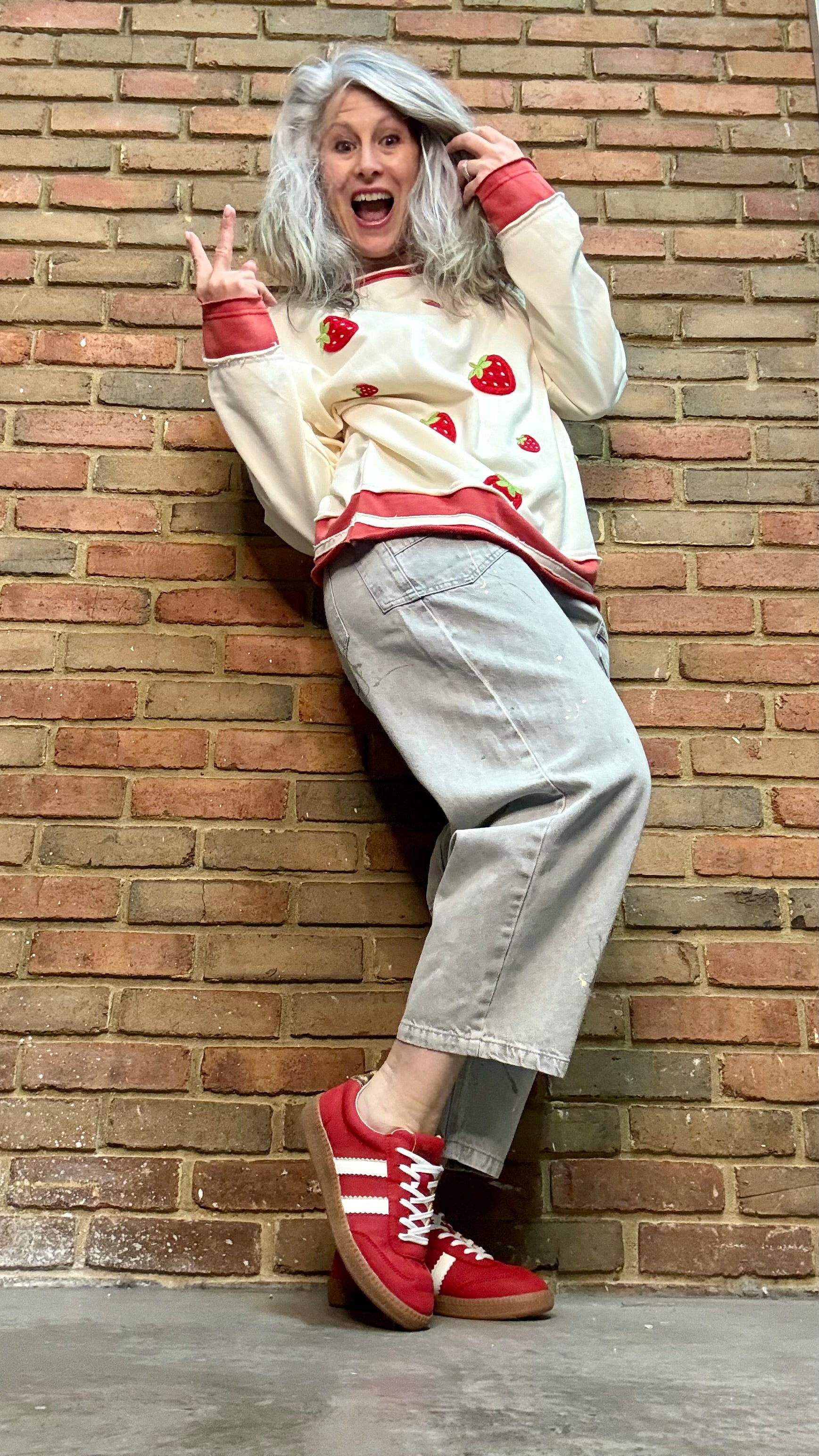 Person wearing Oyster Grey Big Pocket Jeans paired with Strawberry Sweatshirt and Heads Up Red Shoes