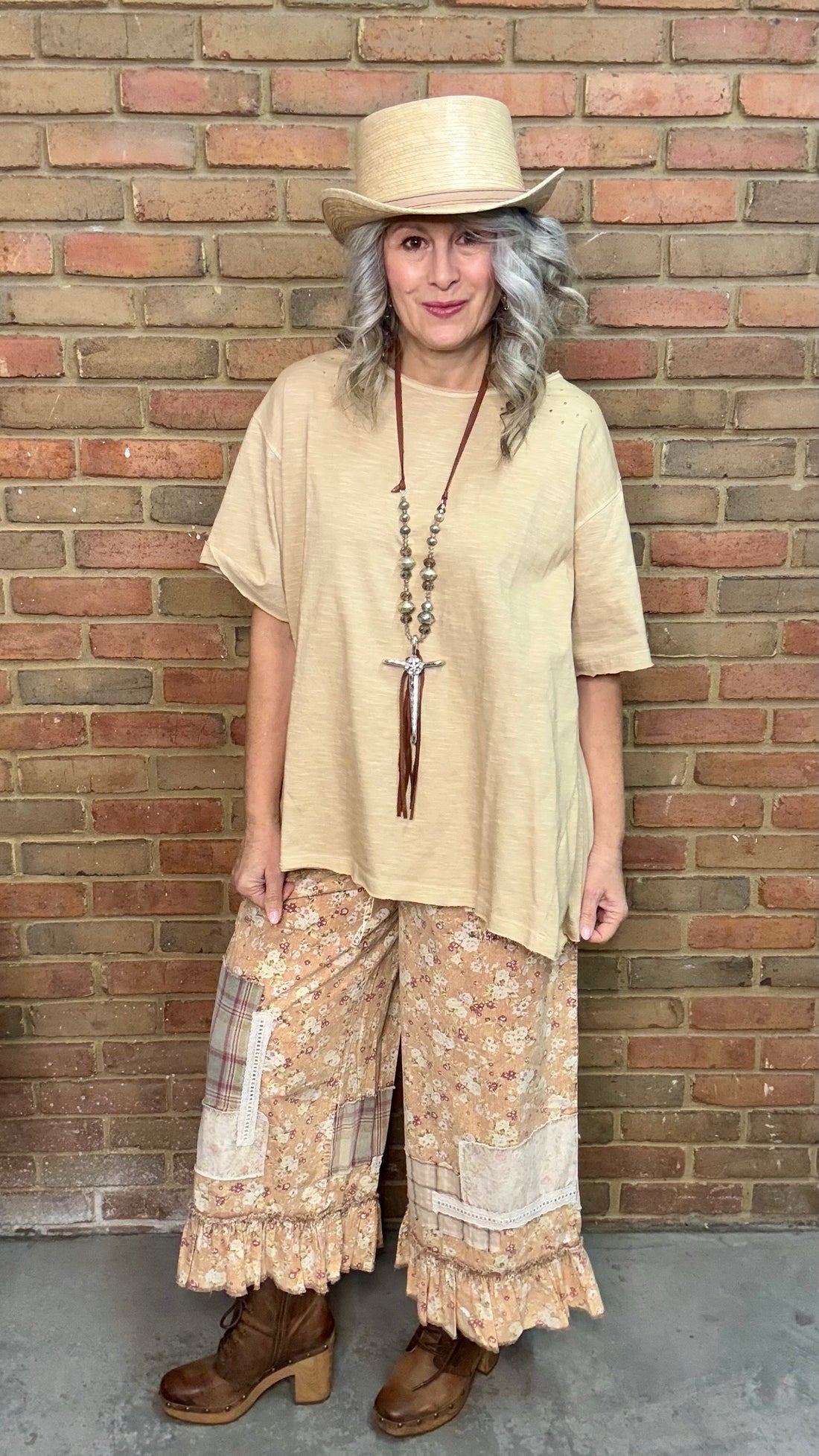 Woman wearing a beige sleeveless top with a Hammered Cross Necklace against a brick wall.