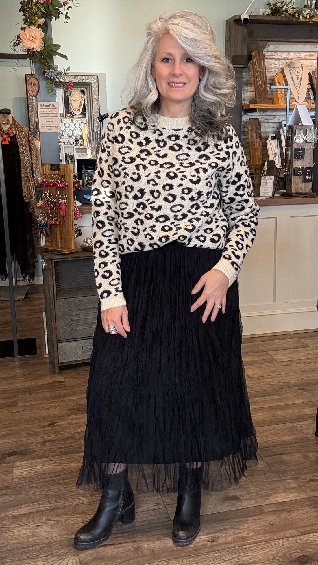 Woman wearing a leopard print sweater and black skirt in a store setting