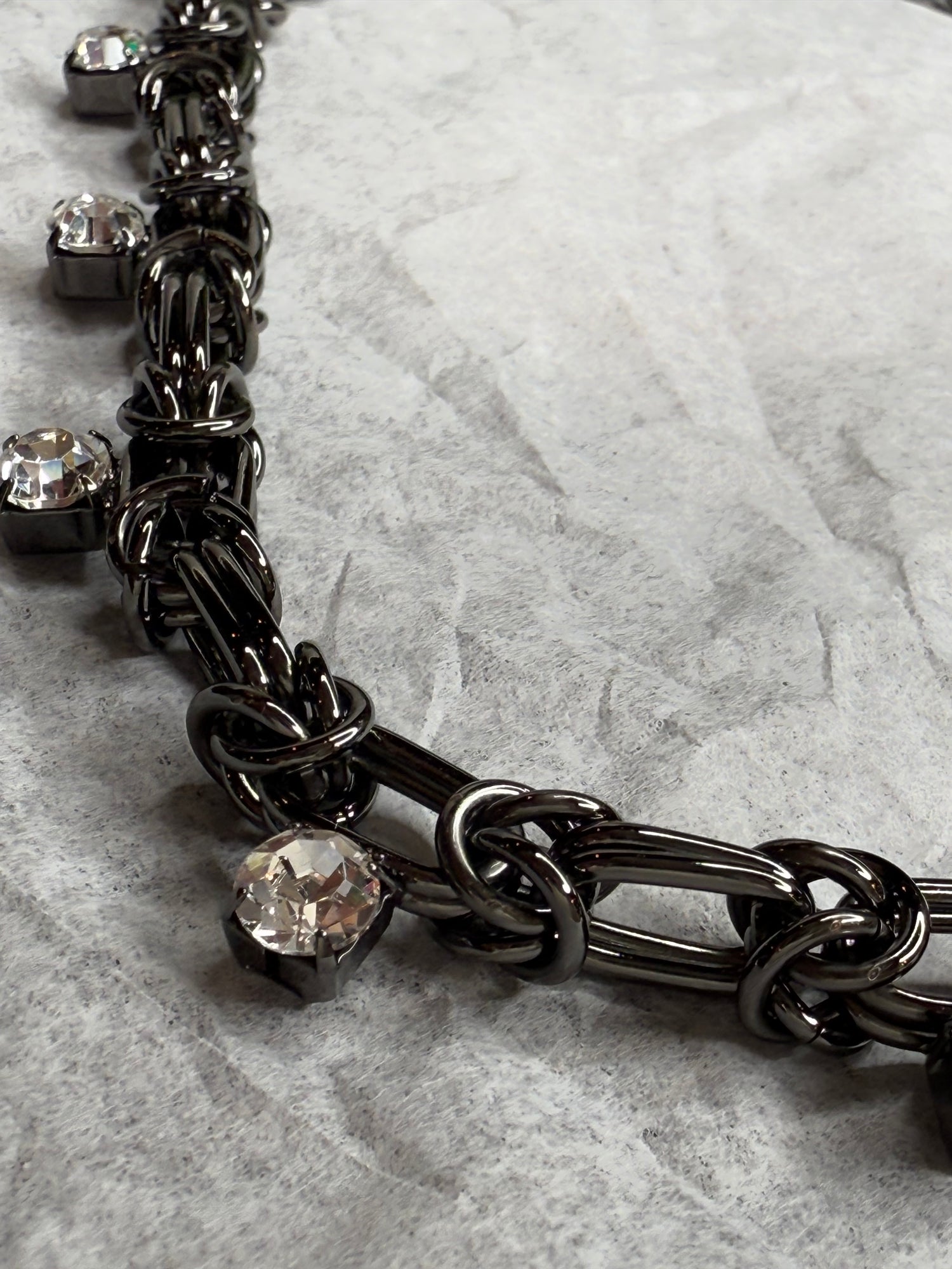 Black chain necklace with crystal stones on a marble surface