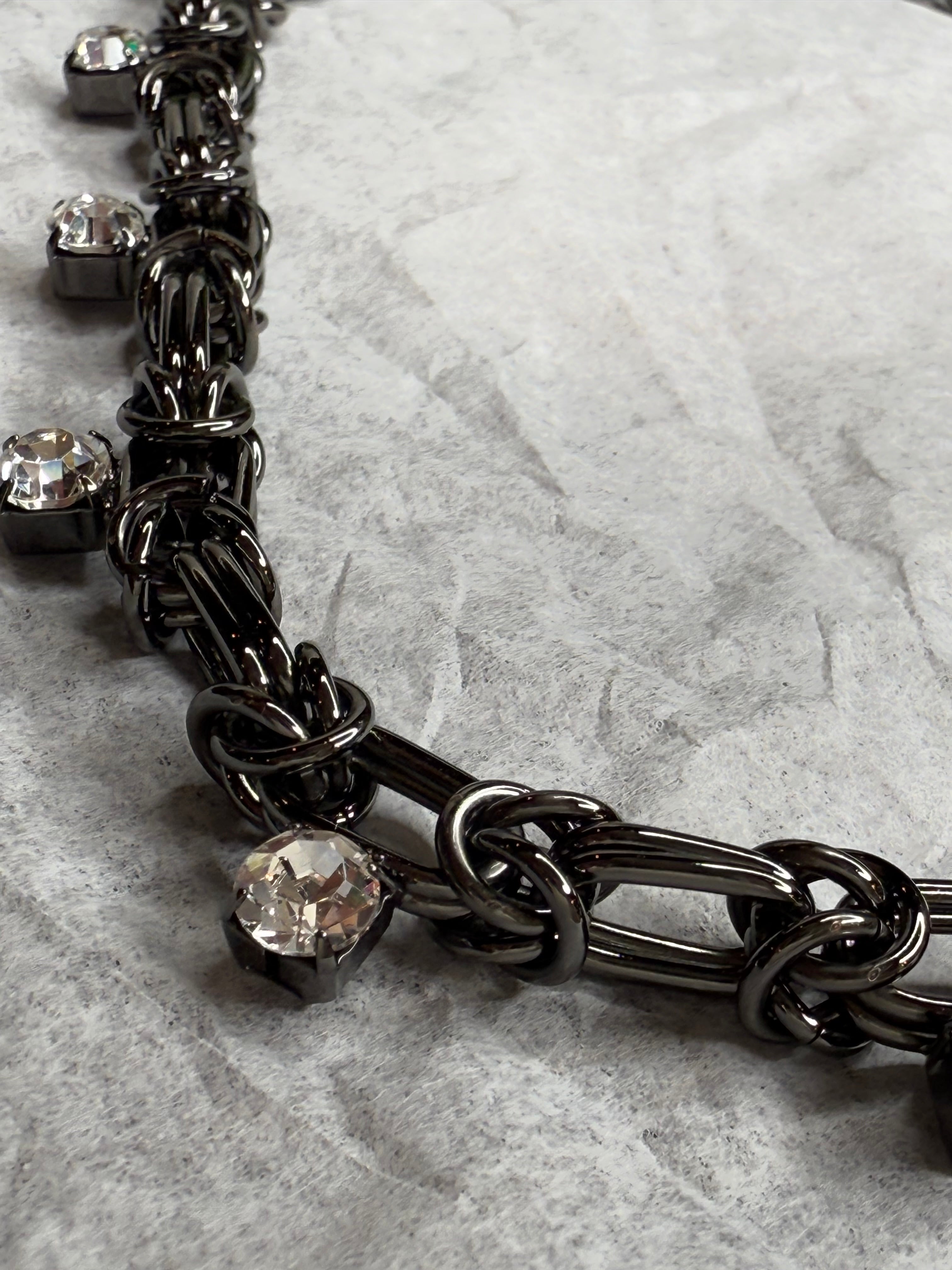 Black chain necklace with crystal stones on a marble surface