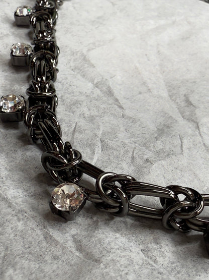 Black chain necklace with crystal stones on a marble surface