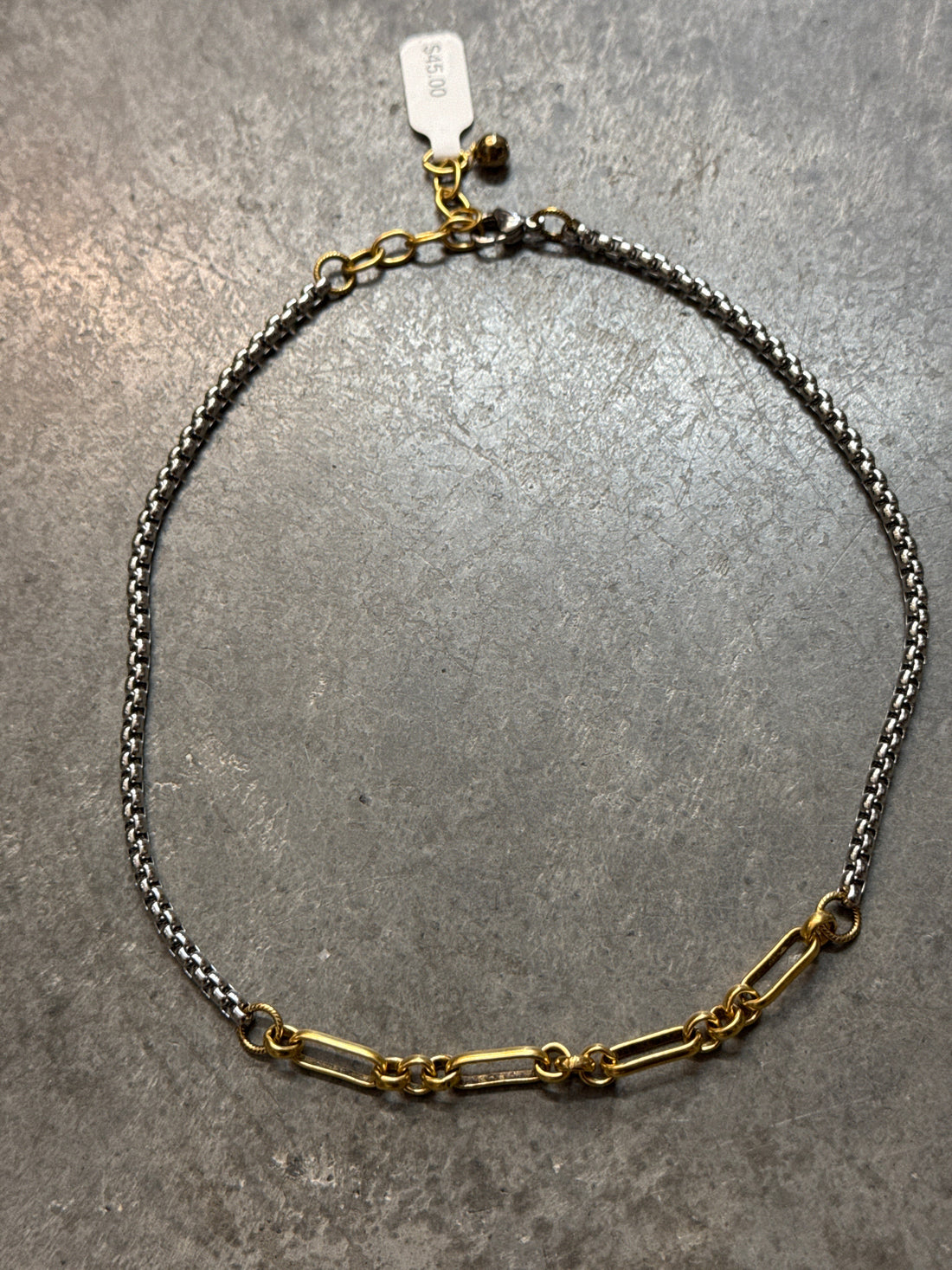 Gold and silver chain necklace on a gray surface