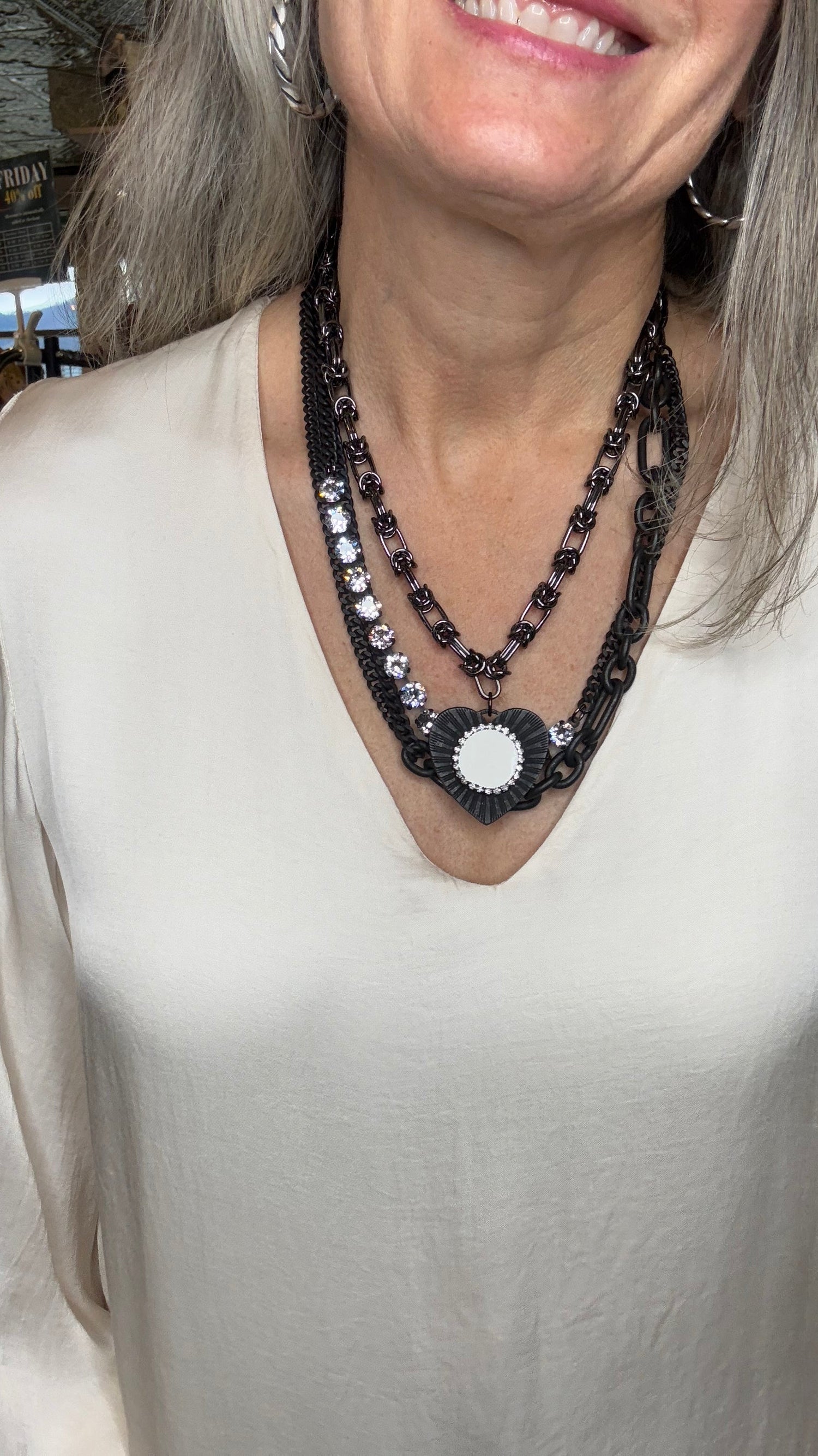 Close-up of a person wearing a black beaded necklace with a white garment.