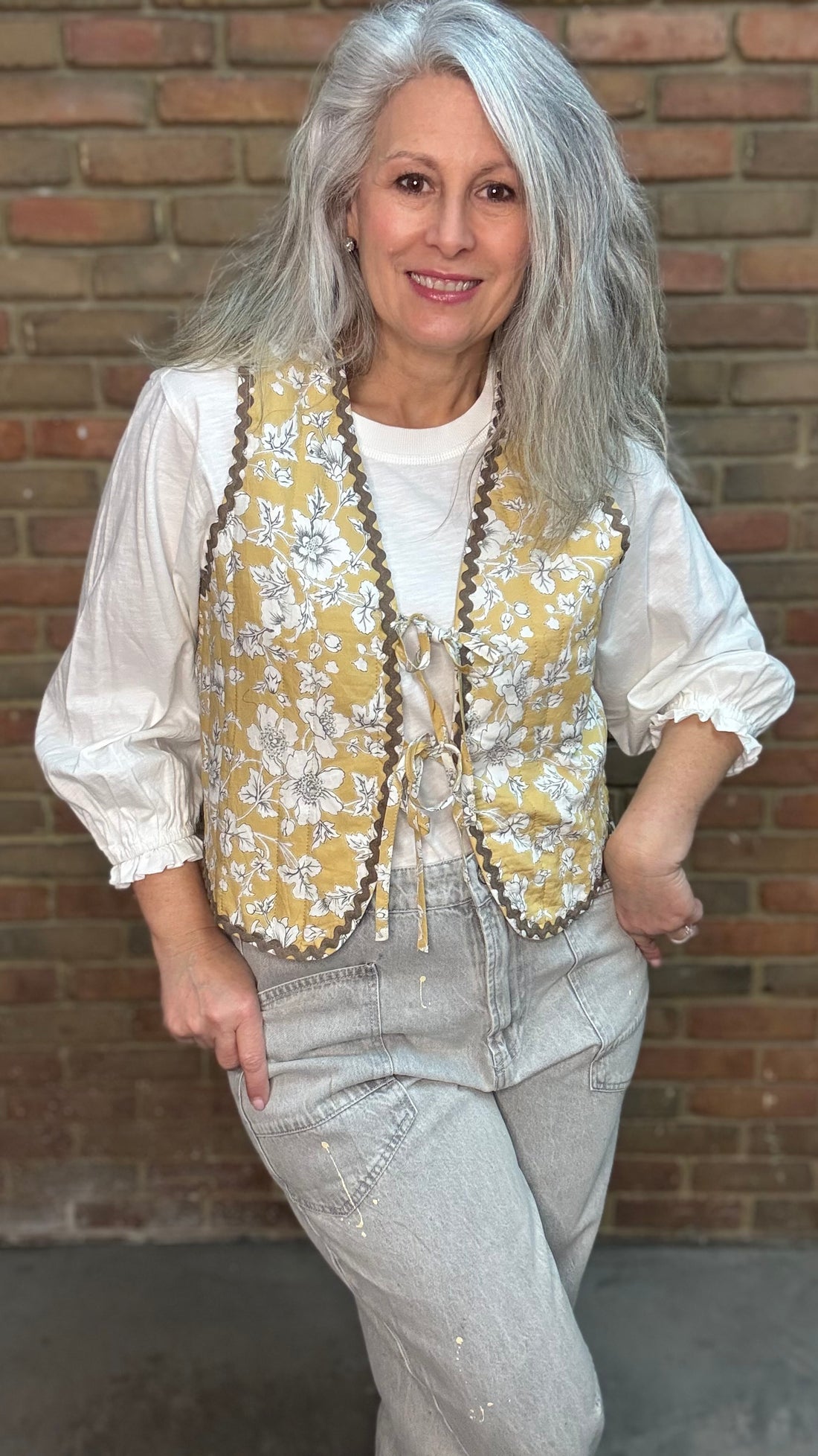 Woman wearing a Quilted Tie Front Vest - Honey Bloom over Basic Long Sleeve Crew Neck Top paired with Oyster Grey Big Pocket Jeans.