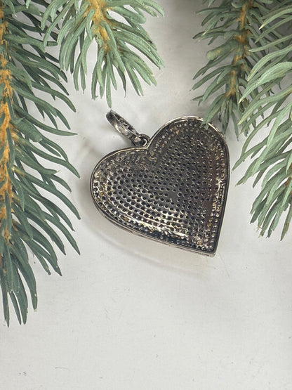 Back of Heart-shaped silver pendant on a light background with greenery