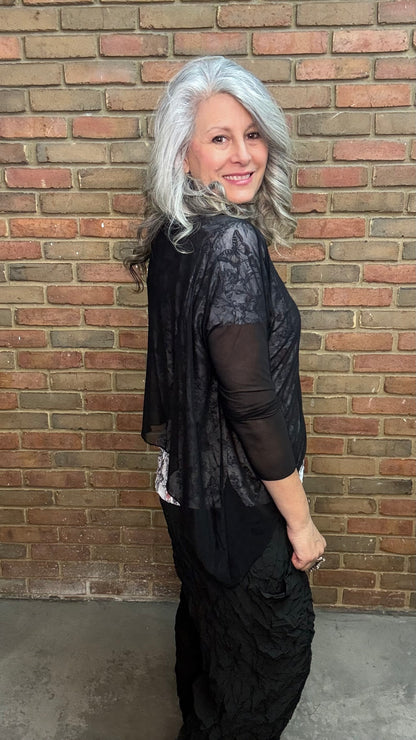 Woman standing against Solid Mesh Topper Black and black pants.