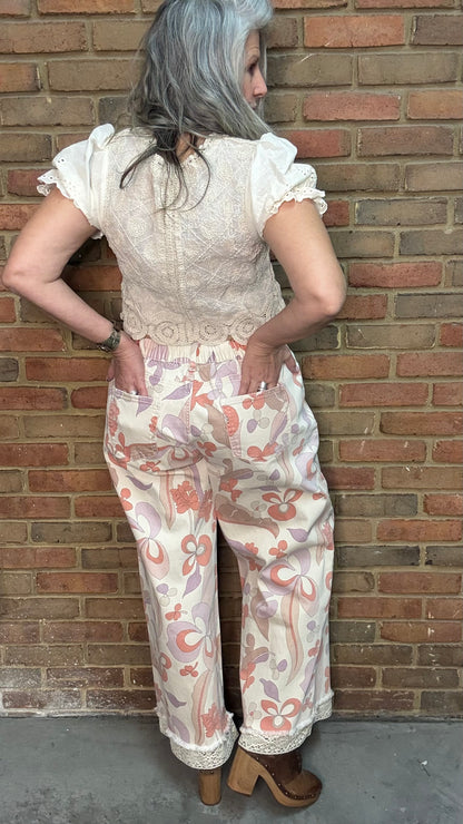 Woman wearing the Groovy Print Denim Pants standing against a brick wall.