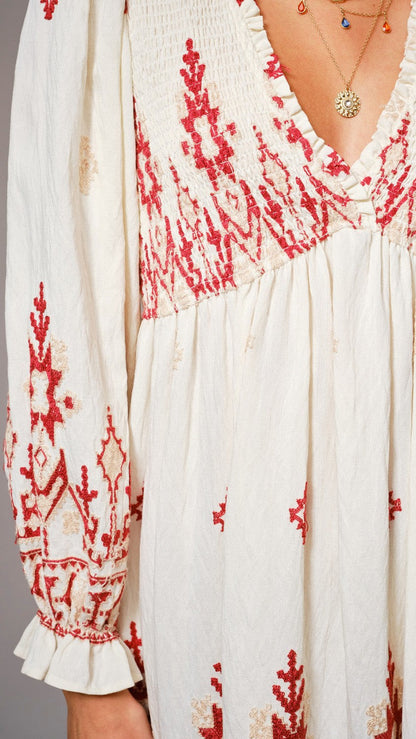 White dress with red and beige floral patterns on a plain background