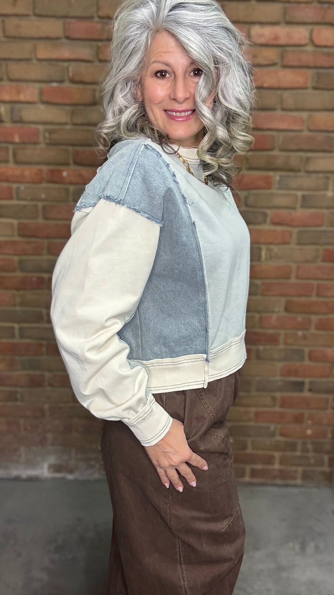Person wearing the Color Block Pullover Top and the brown pullon barrel pants standing against a brick wall.