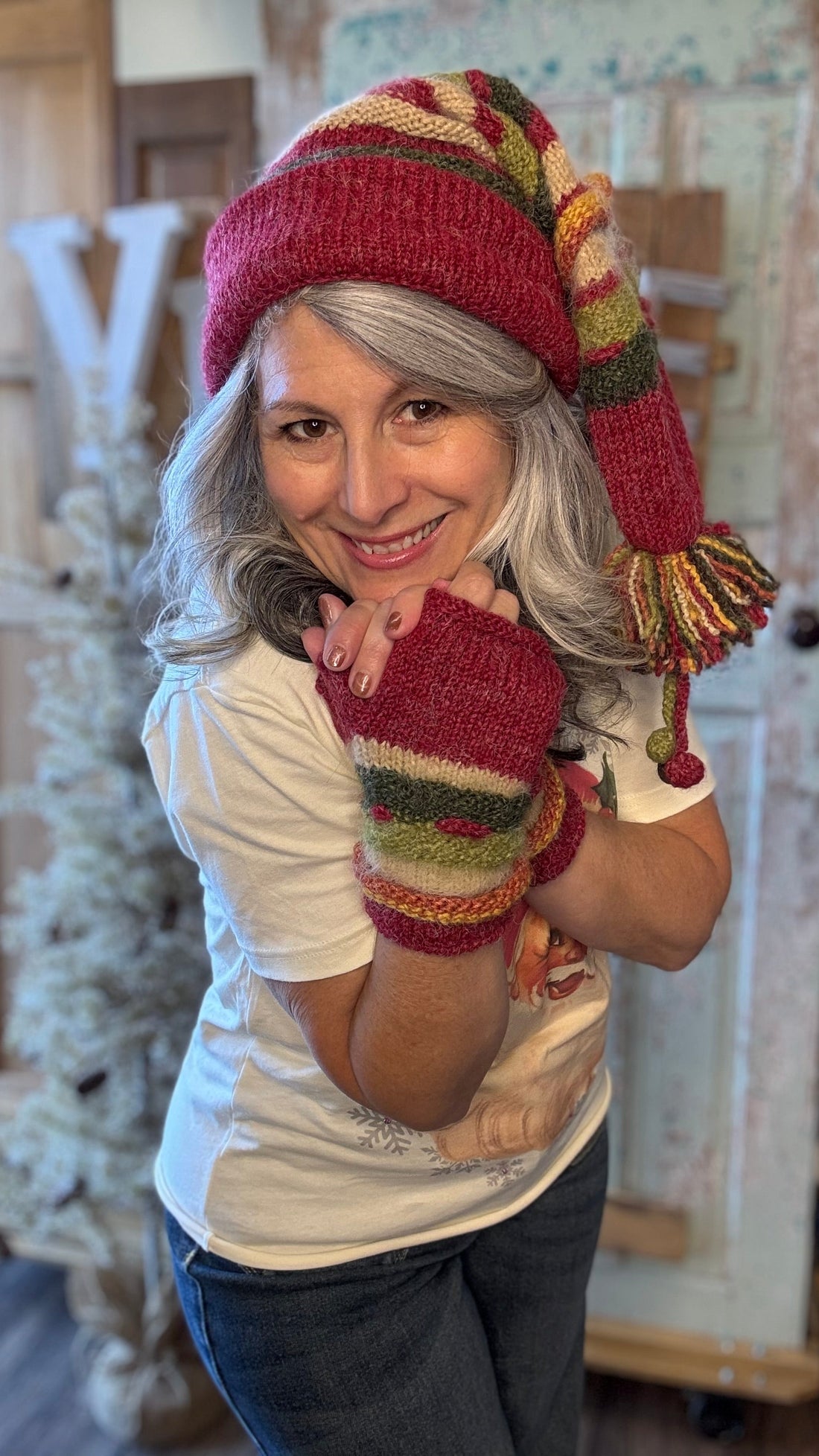 Person wearing a colorful knitted hat and mittens indoors