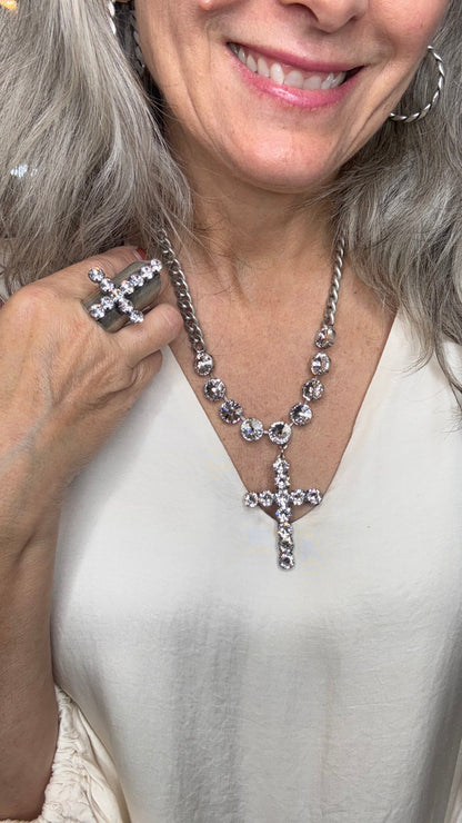Woman wearing a silver necklace with cross designs, smiling.