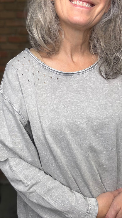 Woman wearing a gray long-sleeve shirt with a blurred background