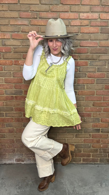 Woman wearing Eyelet Lace Tank over a white shirt, standing against a brick wall.