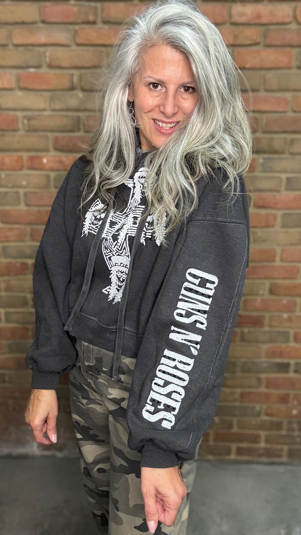 A woman with long silver hair wearing a dark gray Guns N&