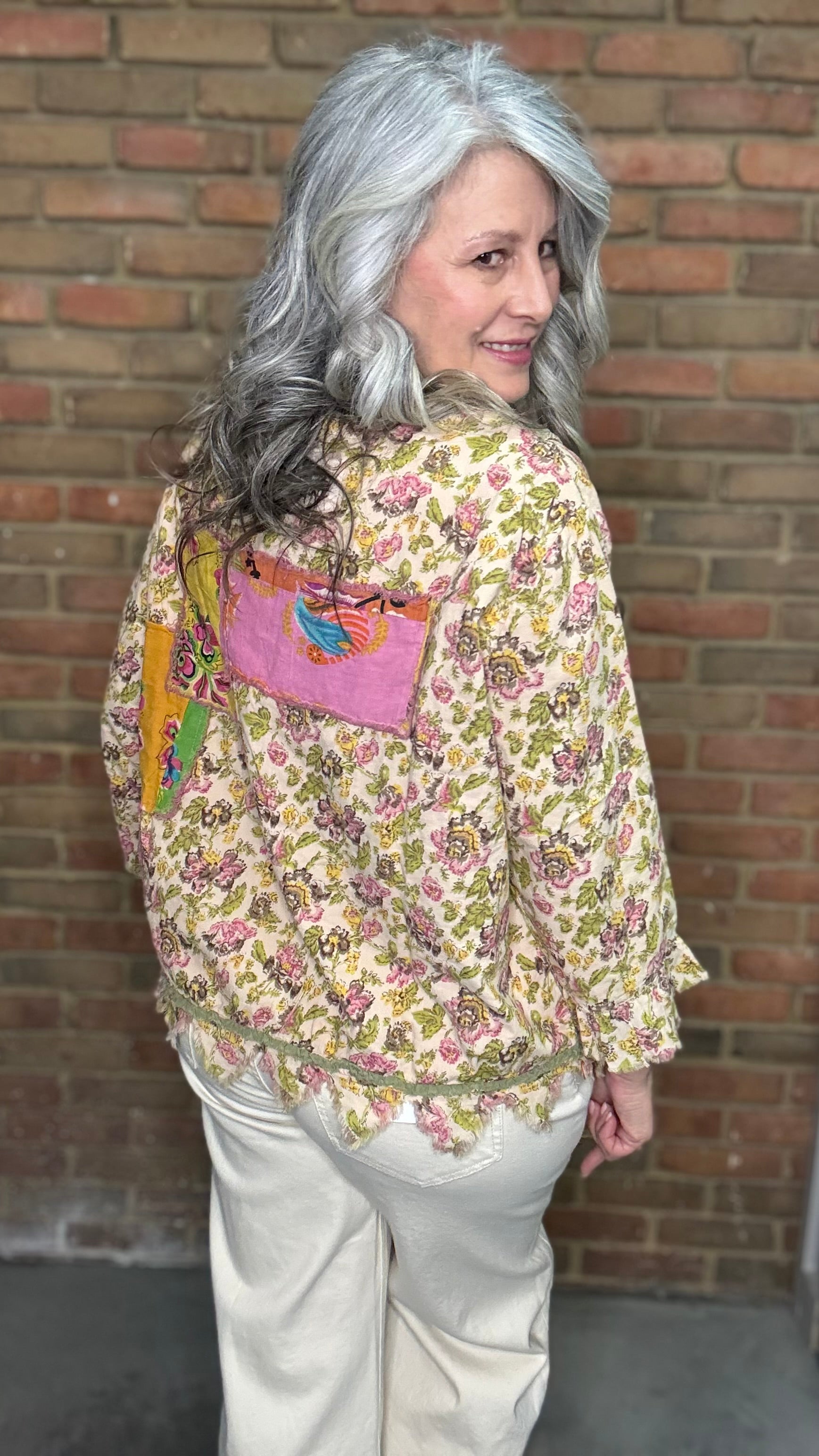 Woman wearing Desert Winds Top against a brick wall.