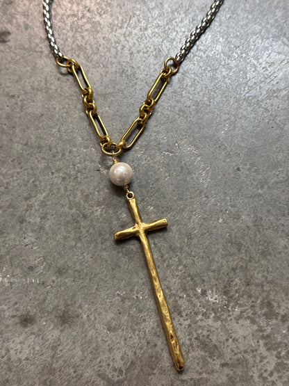 Necklace with a gold cross and pearl pendant on a gray surface