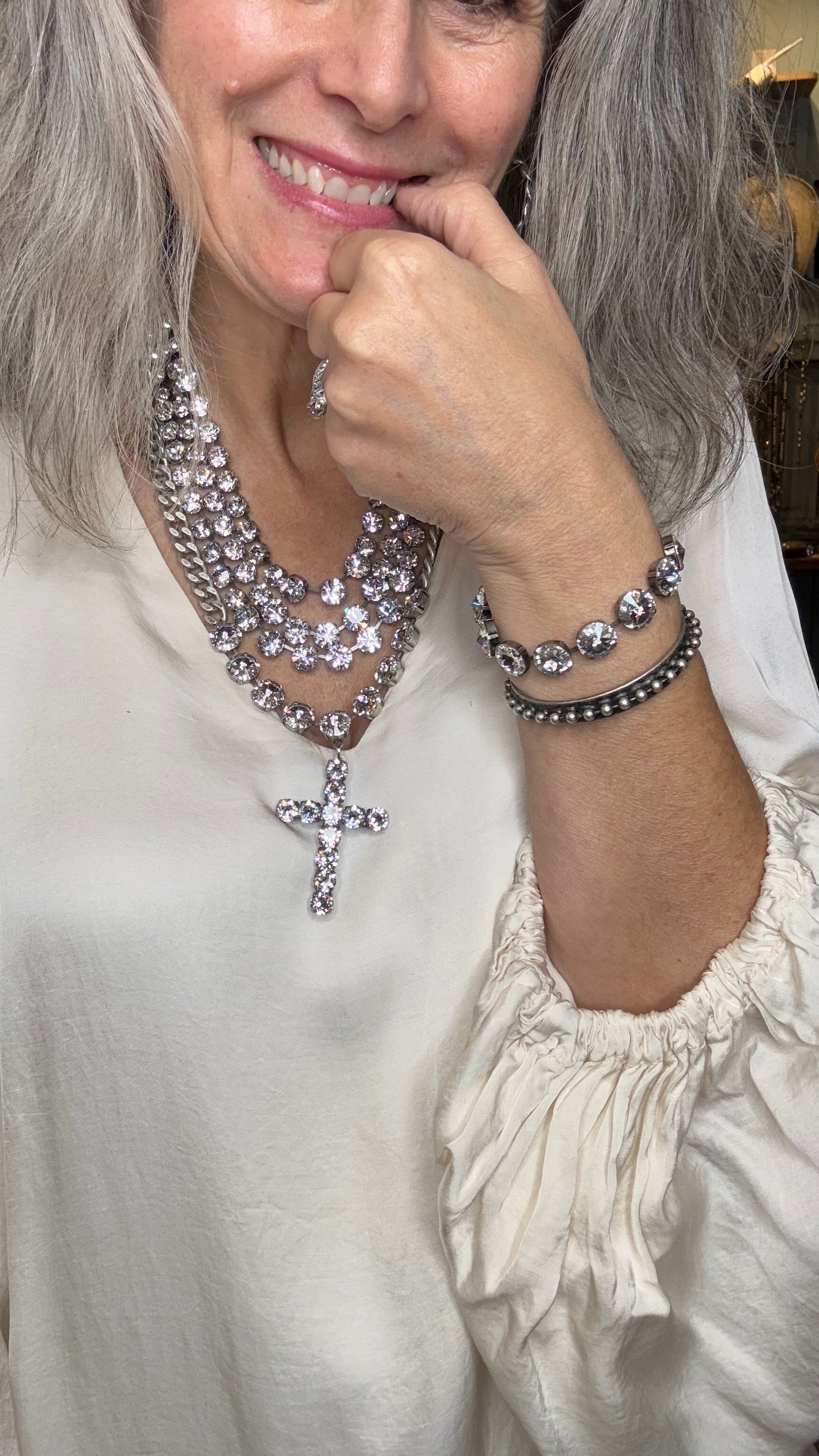 Woman wearing a sparkling necklace and bracelet, with a blurred background
