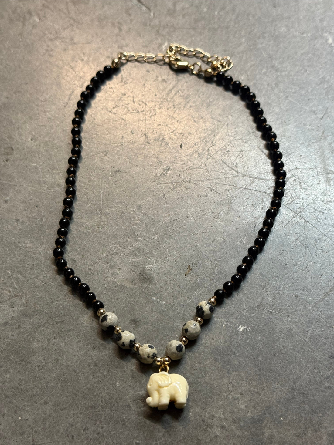 Necklace with black beads and a small decorative element on a gray surface