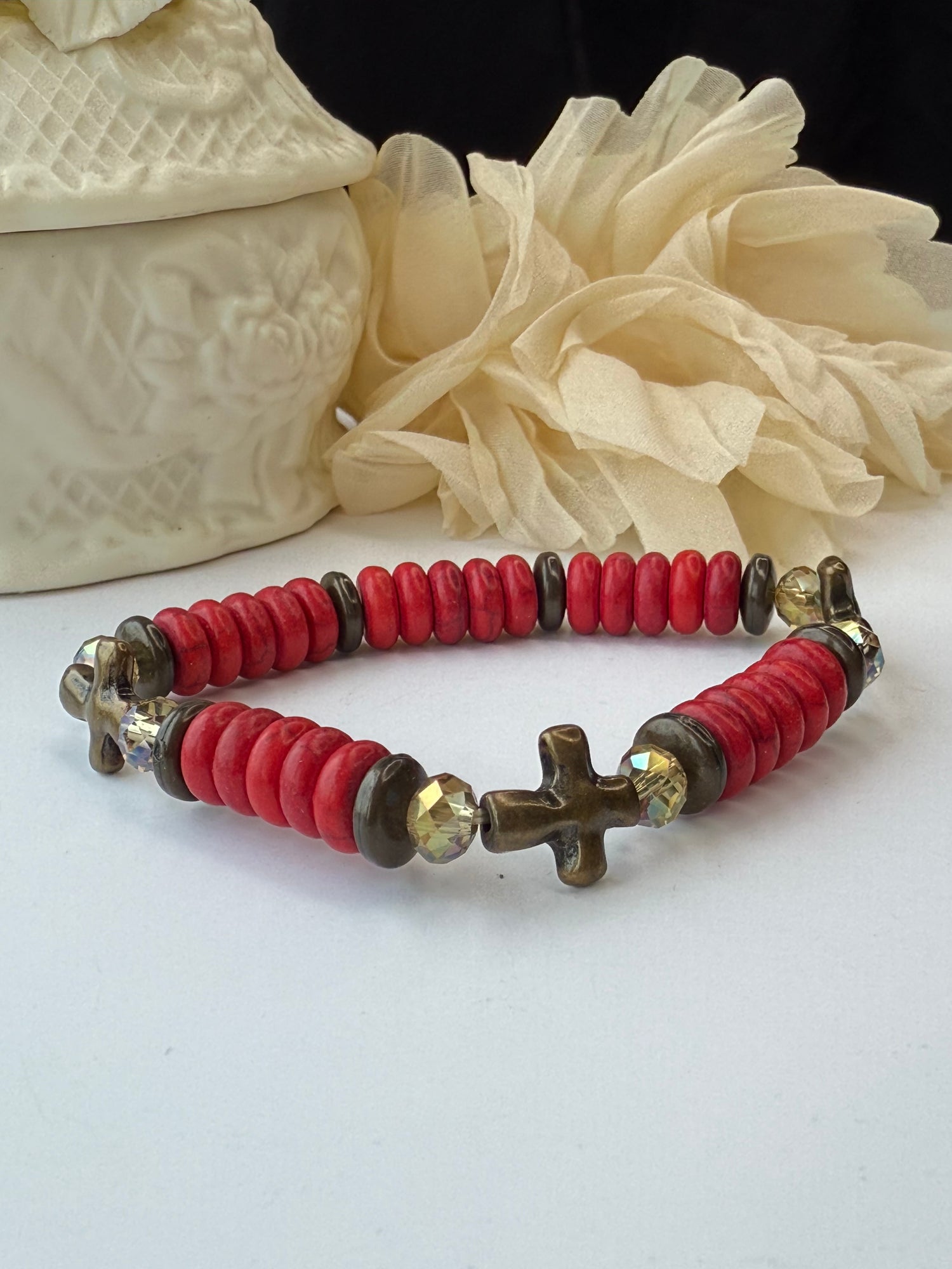 Bracelet with red beads and a cross charm on a white background