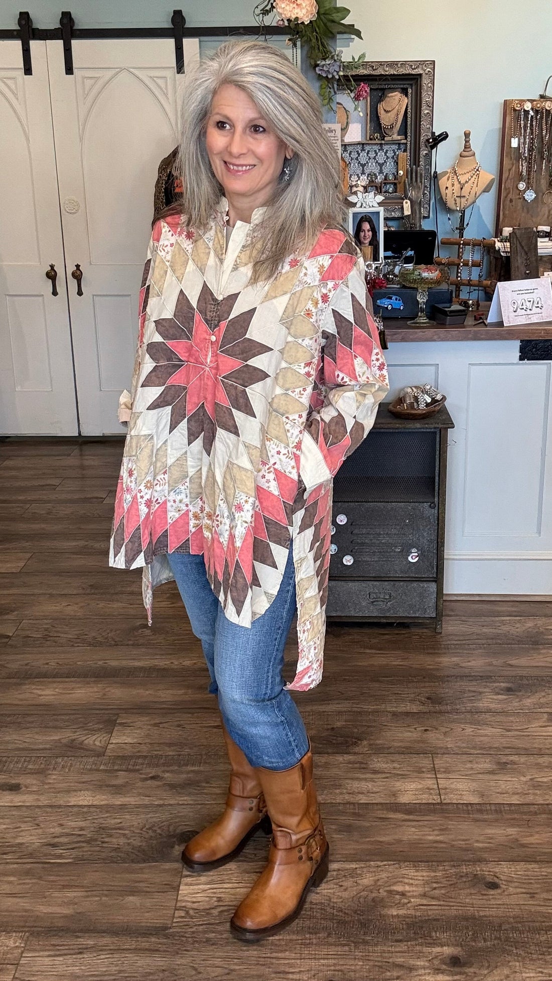 Woman wearing a patterned poncho in a store setting with various items on display.