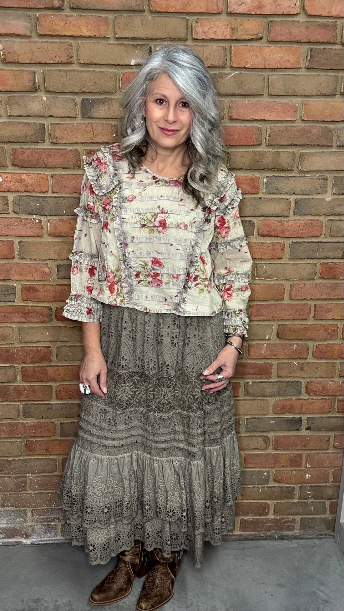 Woman wearing a Vintage Wash Pin Tuck Ruffle Trim Top standing against a brick wall.