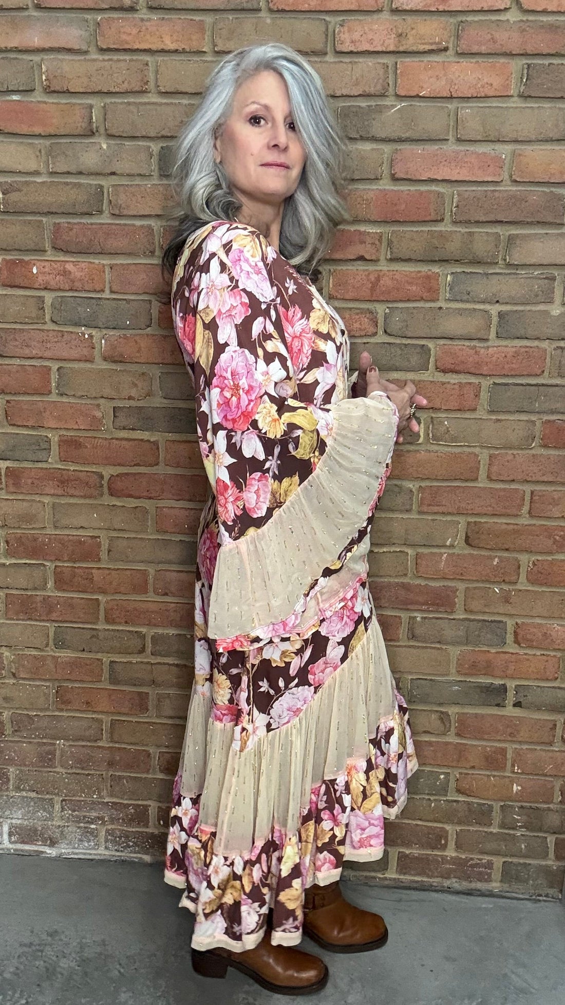 Person wearing a floral dress against a brick wall.