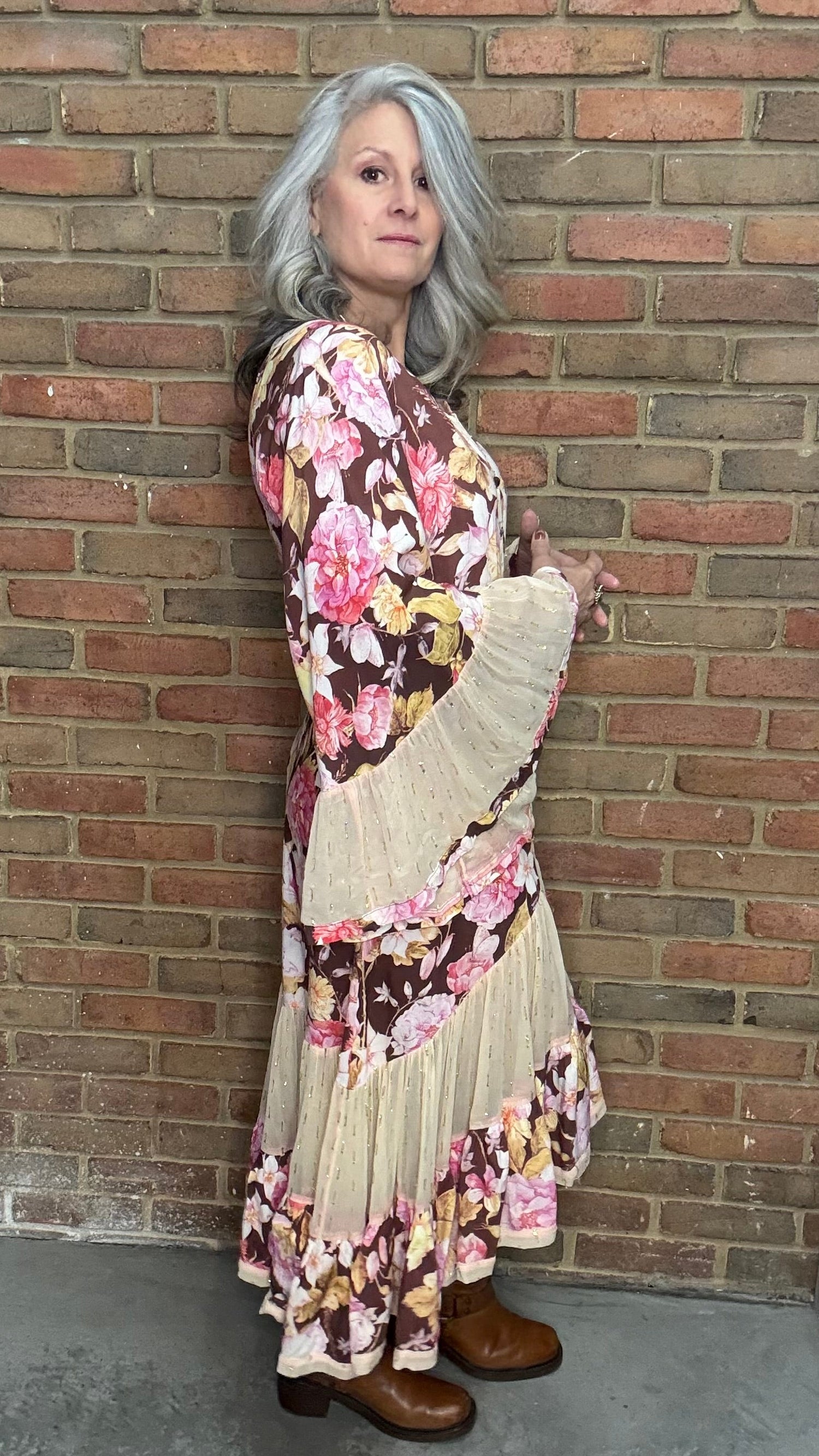 Person wearing a floral dress against a brick wall.
