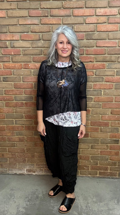 Woman standing against Solid Mesh Topper Black and black pants.