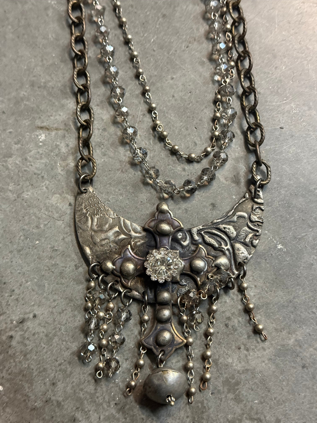 Silver necklace with intricate design on a gray surface