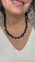 Close-up of a person wearing a black beaded necklace with a white background