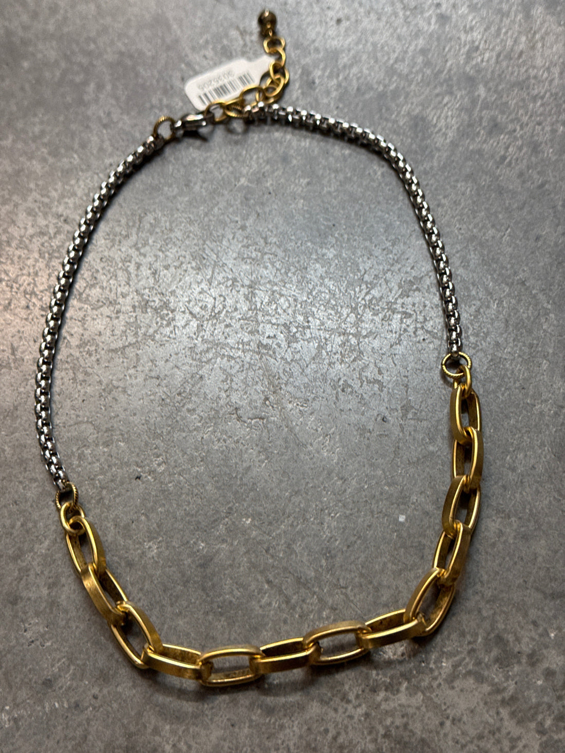 Gold and silver chain necklace on a gray surface