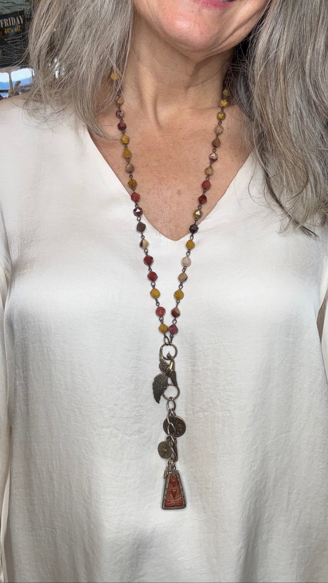 Woman wearing a long beaded necklace with a white top.