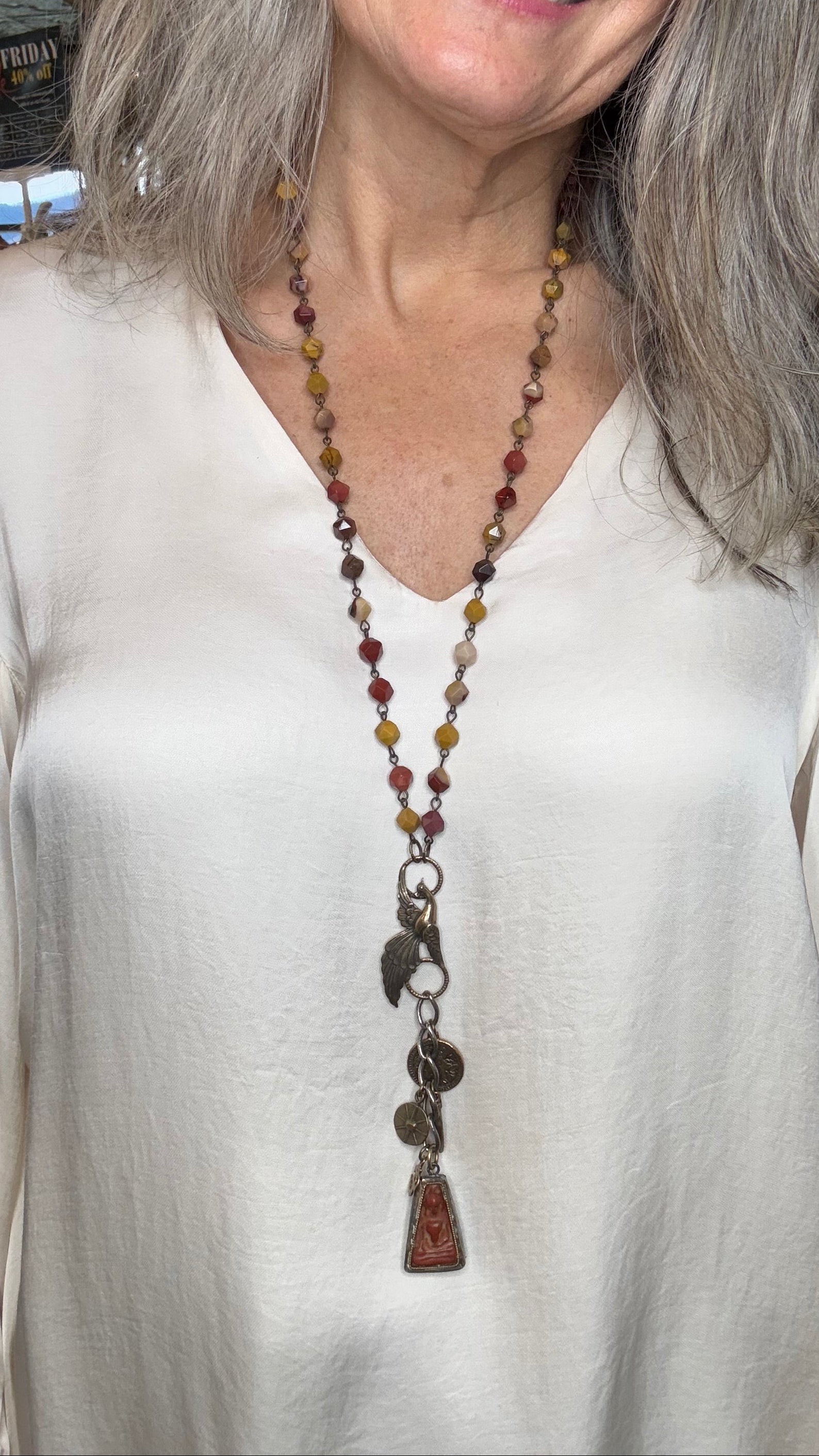Woman wearing a long beaded necklace with a white top.