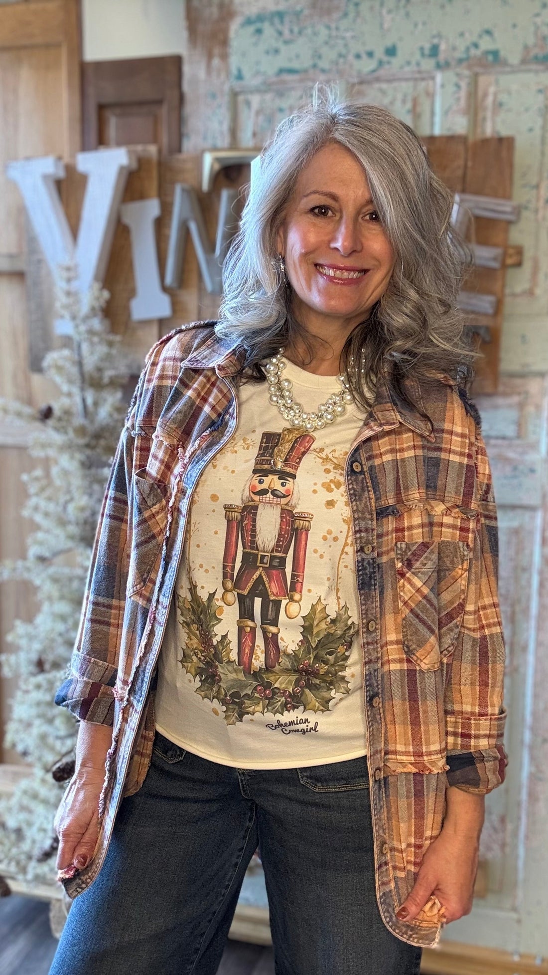 Woman wearing a plaid shirt over a graphic t-shirt with a nutcracker design, standing indoors.