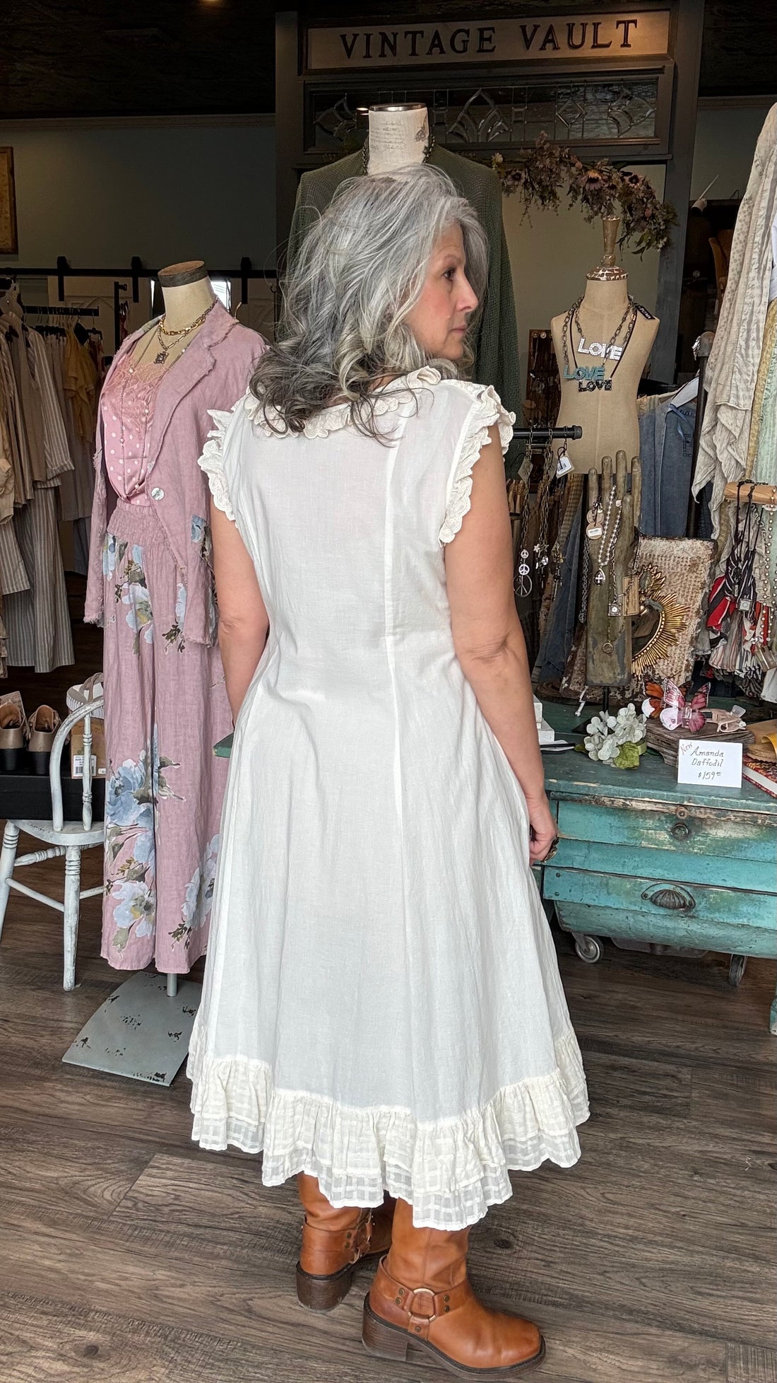 Woman in the ANCOLIE - ECRU DRESS, a off-white dress standing in Vintage Vault with clothing displays in the background.