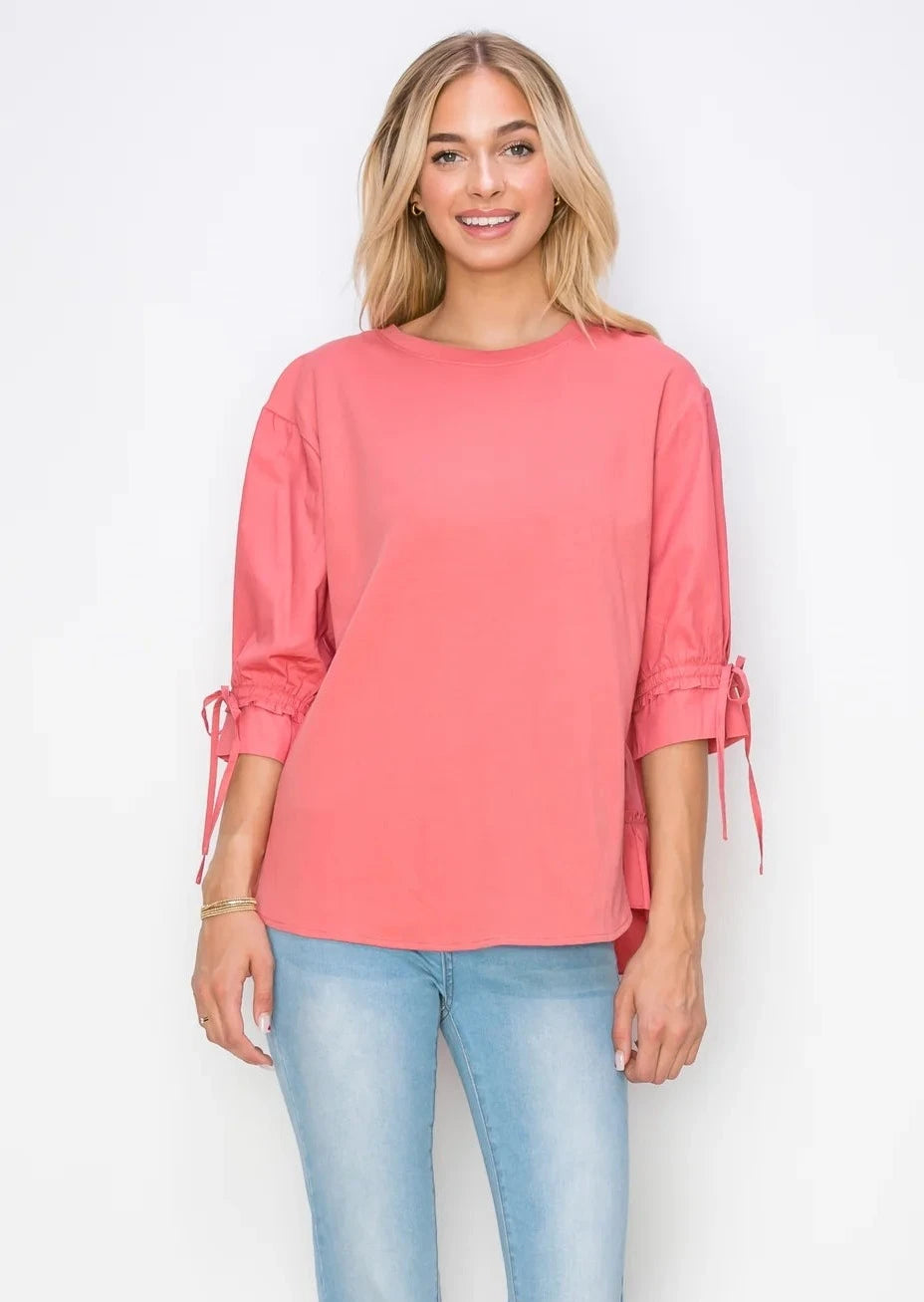 Front view of Reida Pointe Knit Top in Coral, on a model wearing blue jeans.