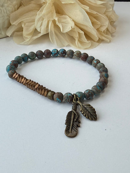 Bracelet with bead design and feather charm on a white background