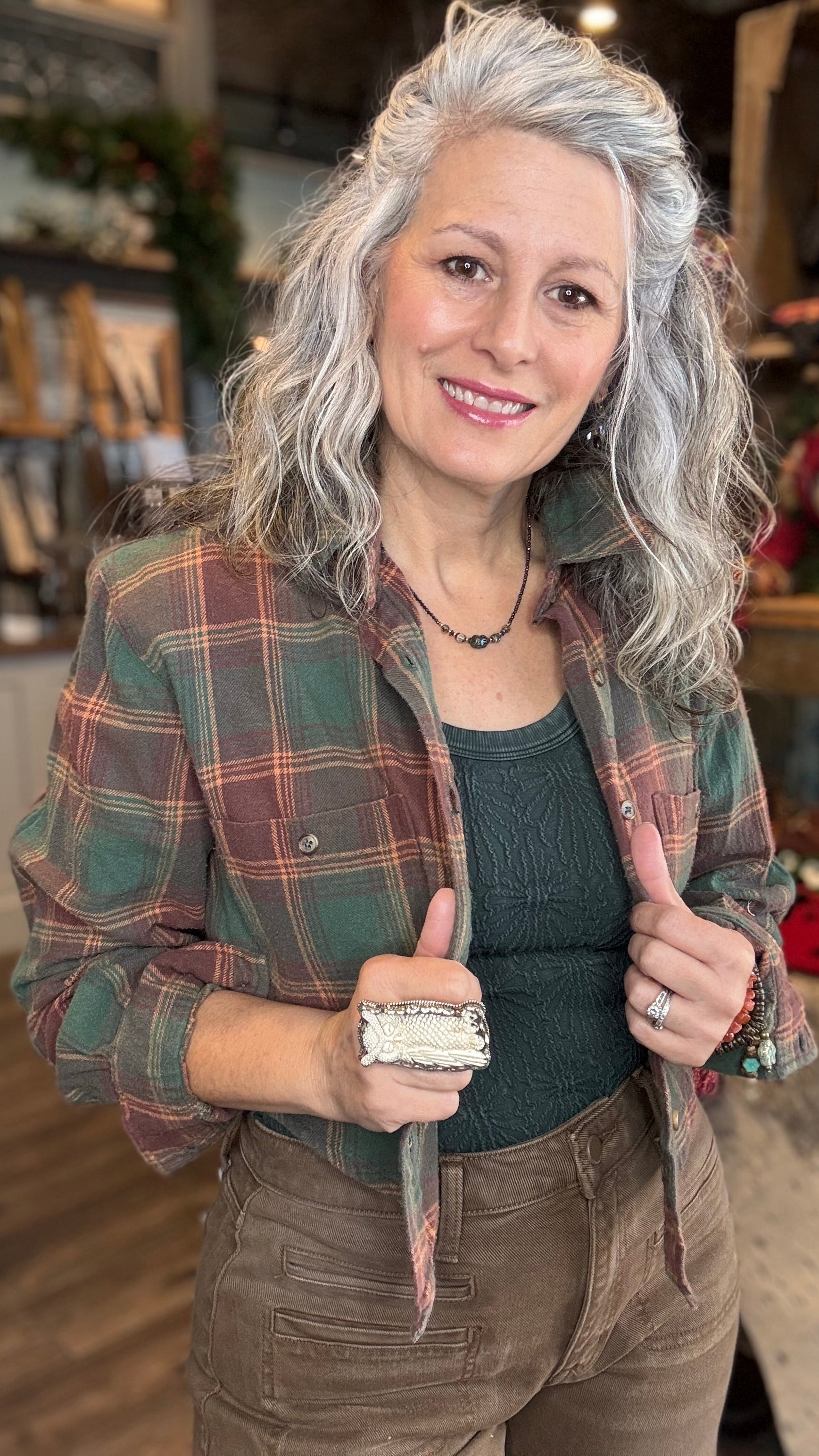 Woman wearing a green plaid crop top and brown barrel jeans in a store setting.