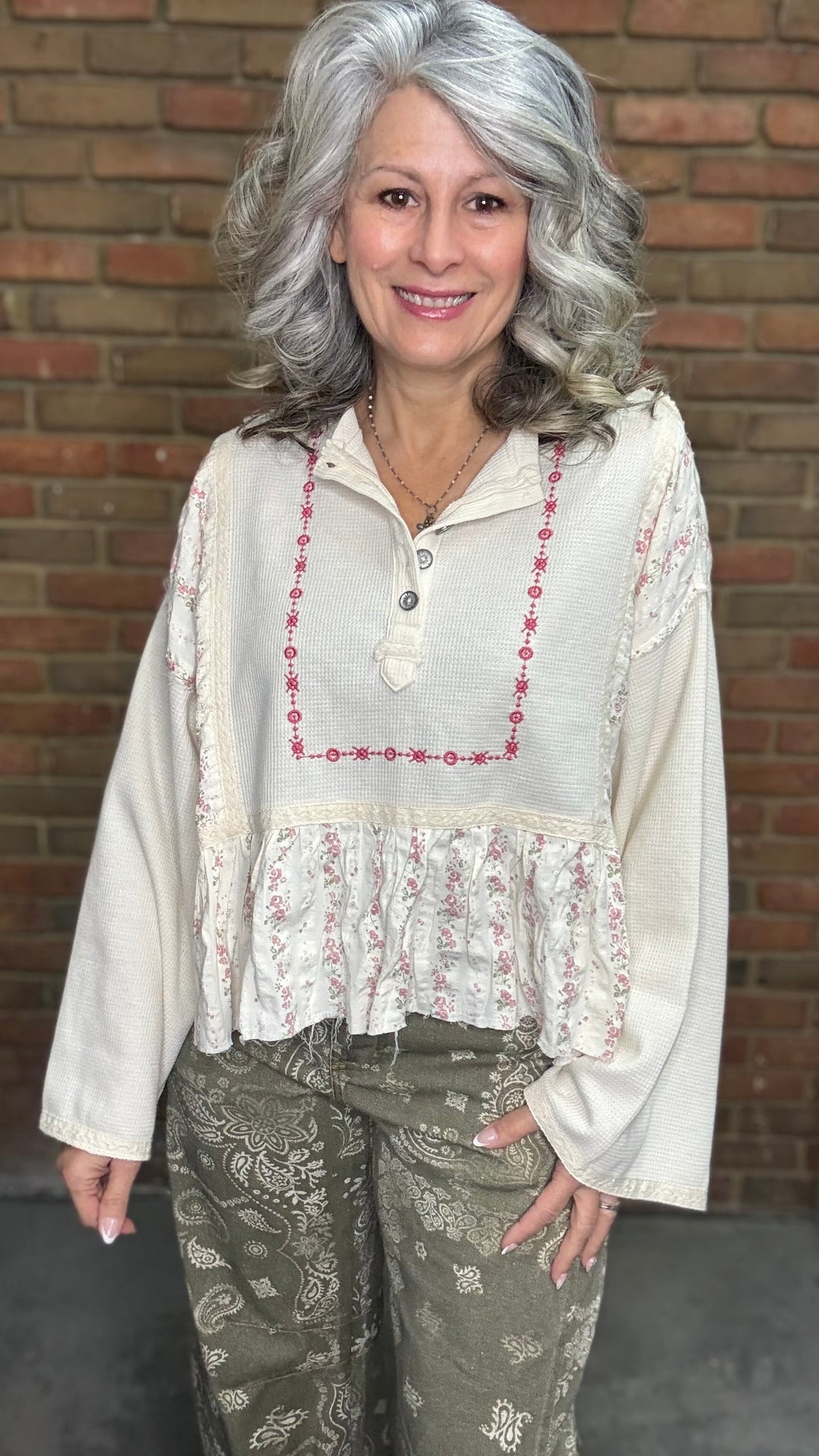 Woman wearing the Natural Flare Sleeve Mix Media Top and Paisley Print Barrel Jean standing against a brick wall.