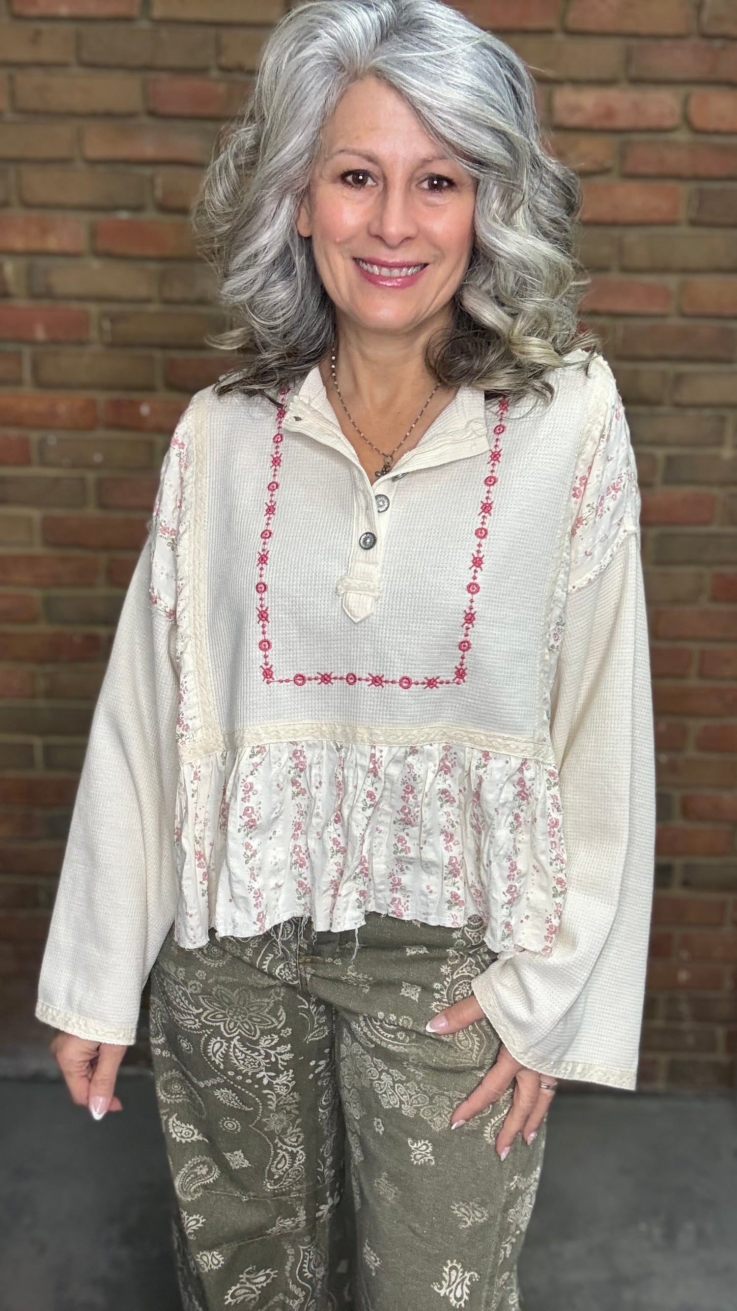 Woman wearing the Natural Flare Sleeve Mix Media Top and Paisley Print Barrel Jean standing against a brick wall.