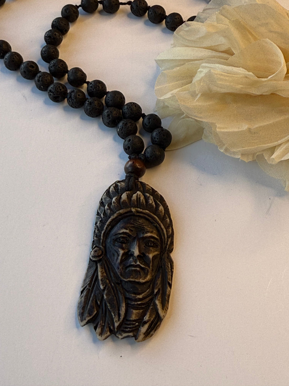 Black beaded necklace with an ornate pendant on a white surface
