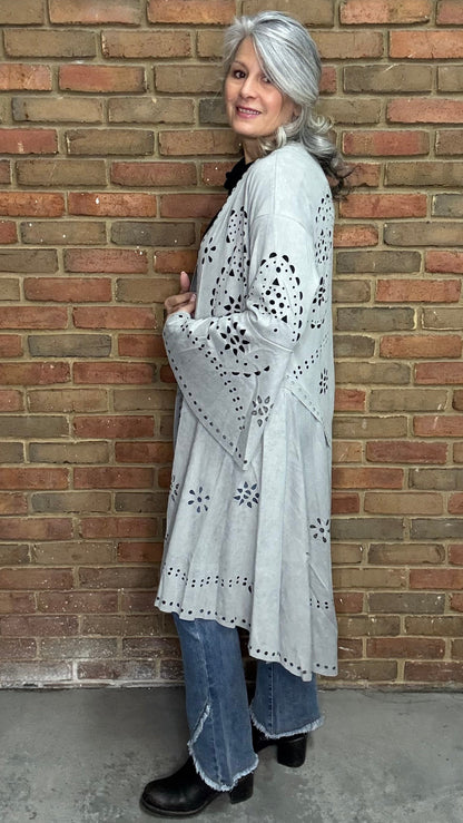 Woman wearing the Grey Suede Laser Cut Jacket standing against a brick wall.