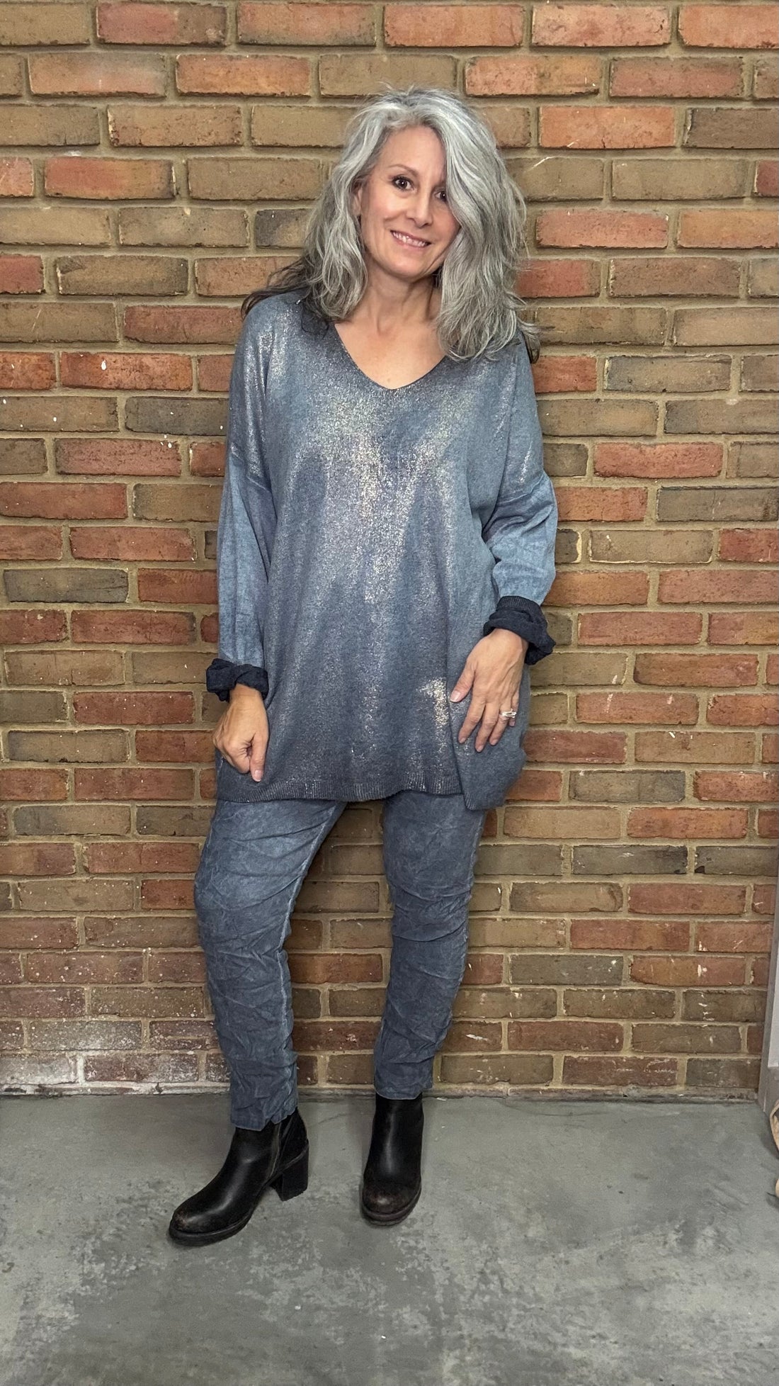 Woman in a blue outfit standing against a brick wall