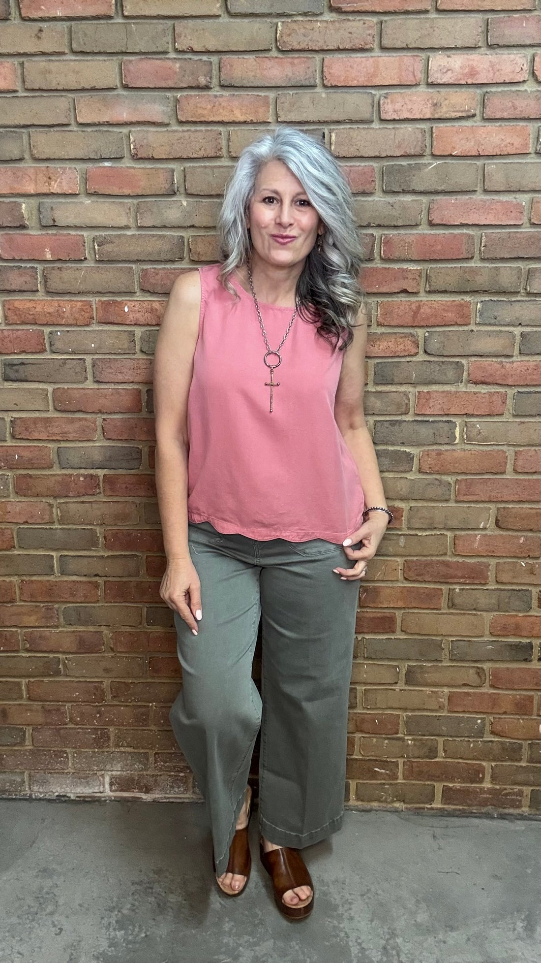 Woman wearing Scallop Hem Button Detail Top with sage pants against a brick wall