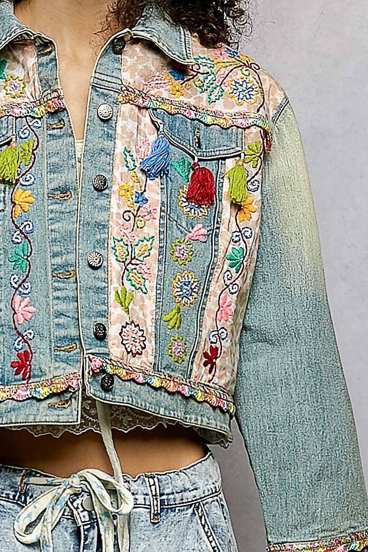 Embroidered denim jacket with colorful floral patterns on a plain background