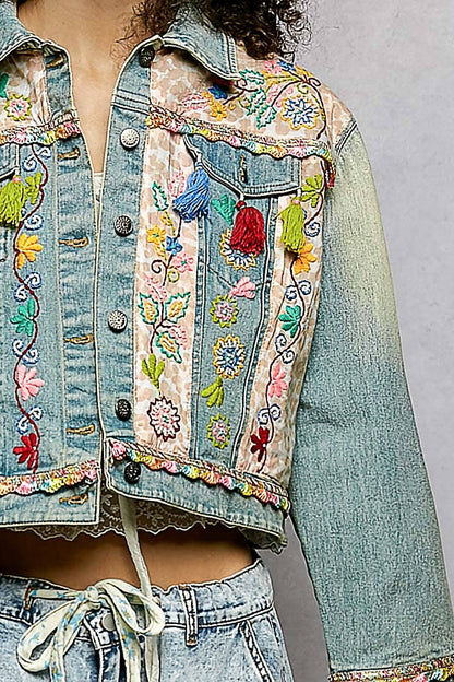 Embroidered denim jacket with colorful floral patterns on a plain background
