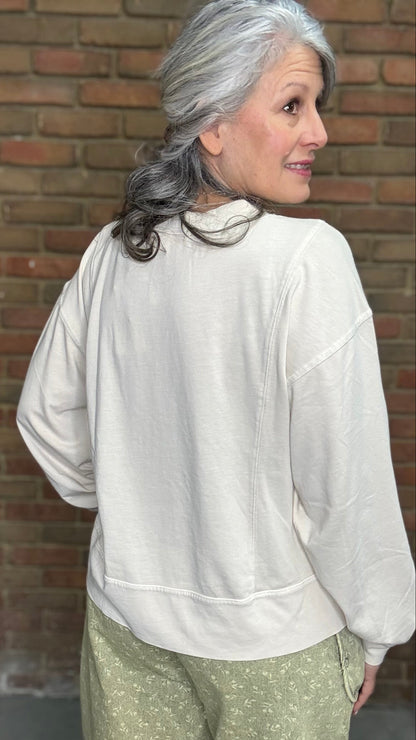 Woman standing against a brick wall wearing the Taupe Long Sleeve Top and Floral Printed Barrel Pants.